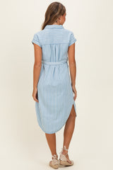 woman wearing a light blue striped shirt dress with a tied waist and rolled sleeves, viewed from the back