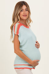 woman wearing a light blue maternity sweater with orange details and holding her baby bump