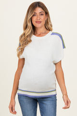 woman wearing a white maternity sweater with colorful striped accents and a visible baby bump