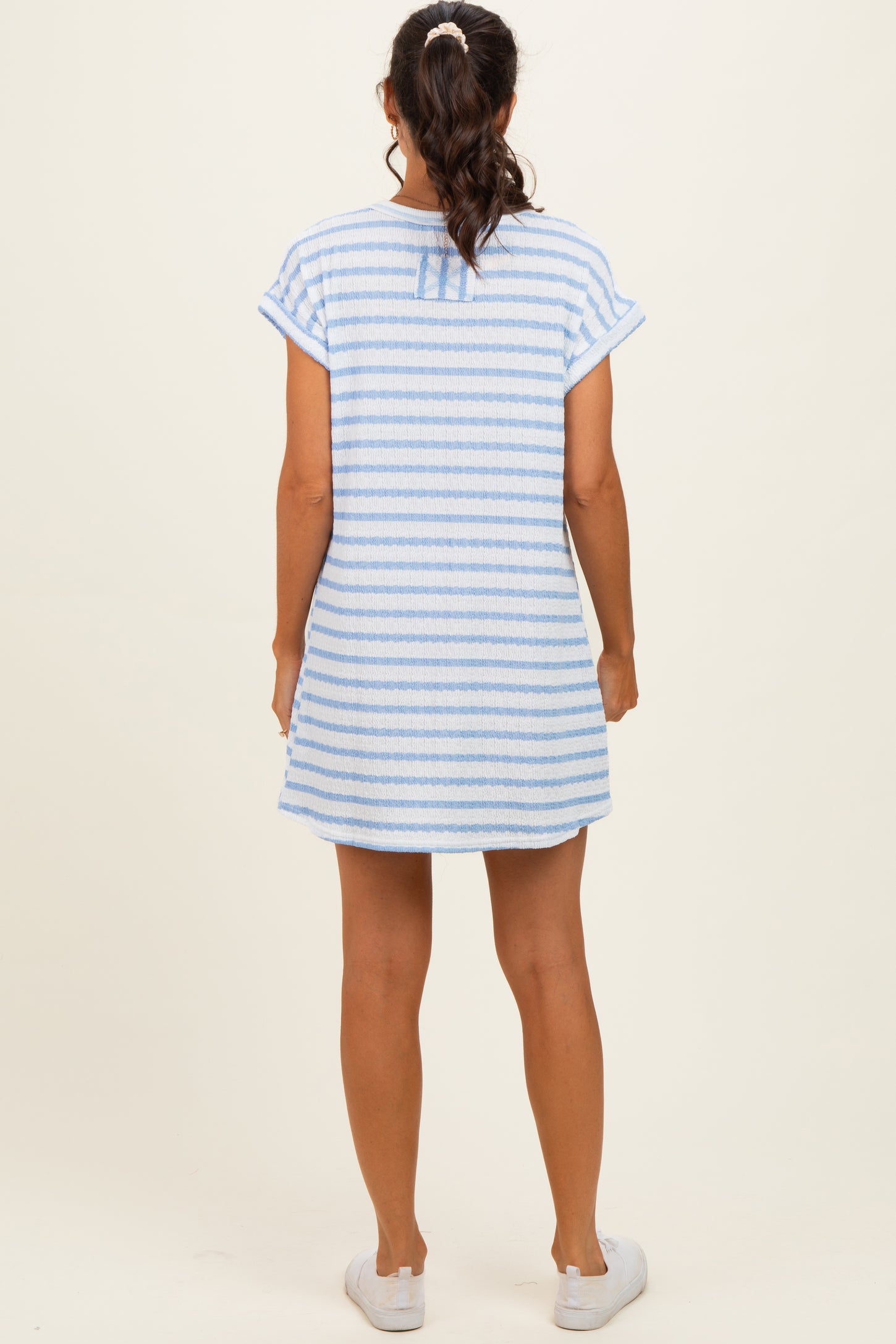 woman wearing a light blue and white striped short sleeve dress viewed from the back