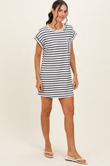 woman wearing a striped black and white short sleeve dress with a pocket, standing and wearing flip flops