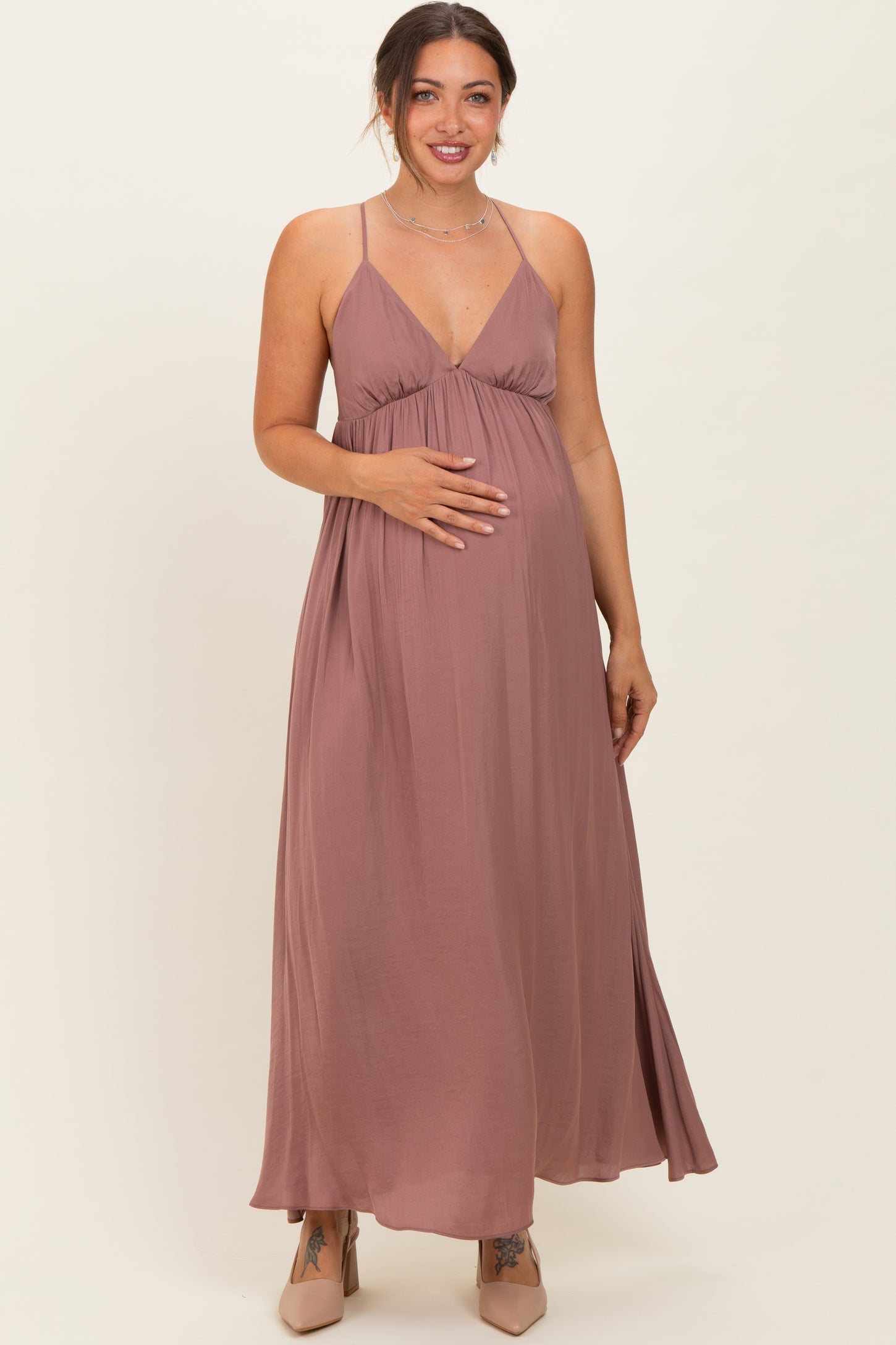 woman wearing a mauve maternity maxi dress with a flattering empire waist and holding her baby bump