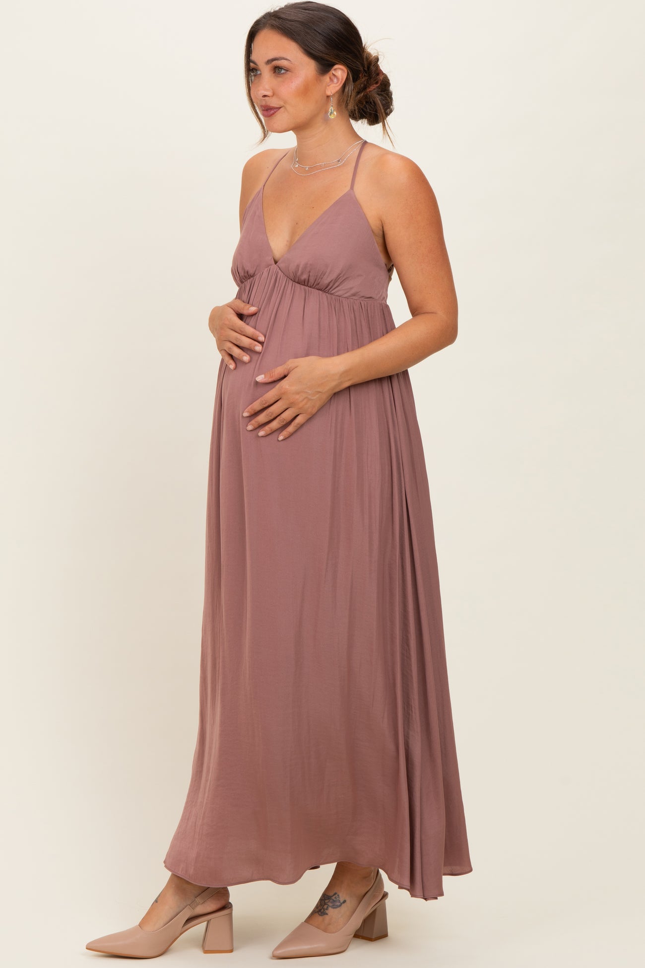 woman wearing a dusty rose maternity maxi dress with a v-neckline, gently cradling her baby bump