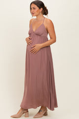 woman wearing a dusty rose maternity maxi dress with a v-neckline, gently cradling her baby bump
