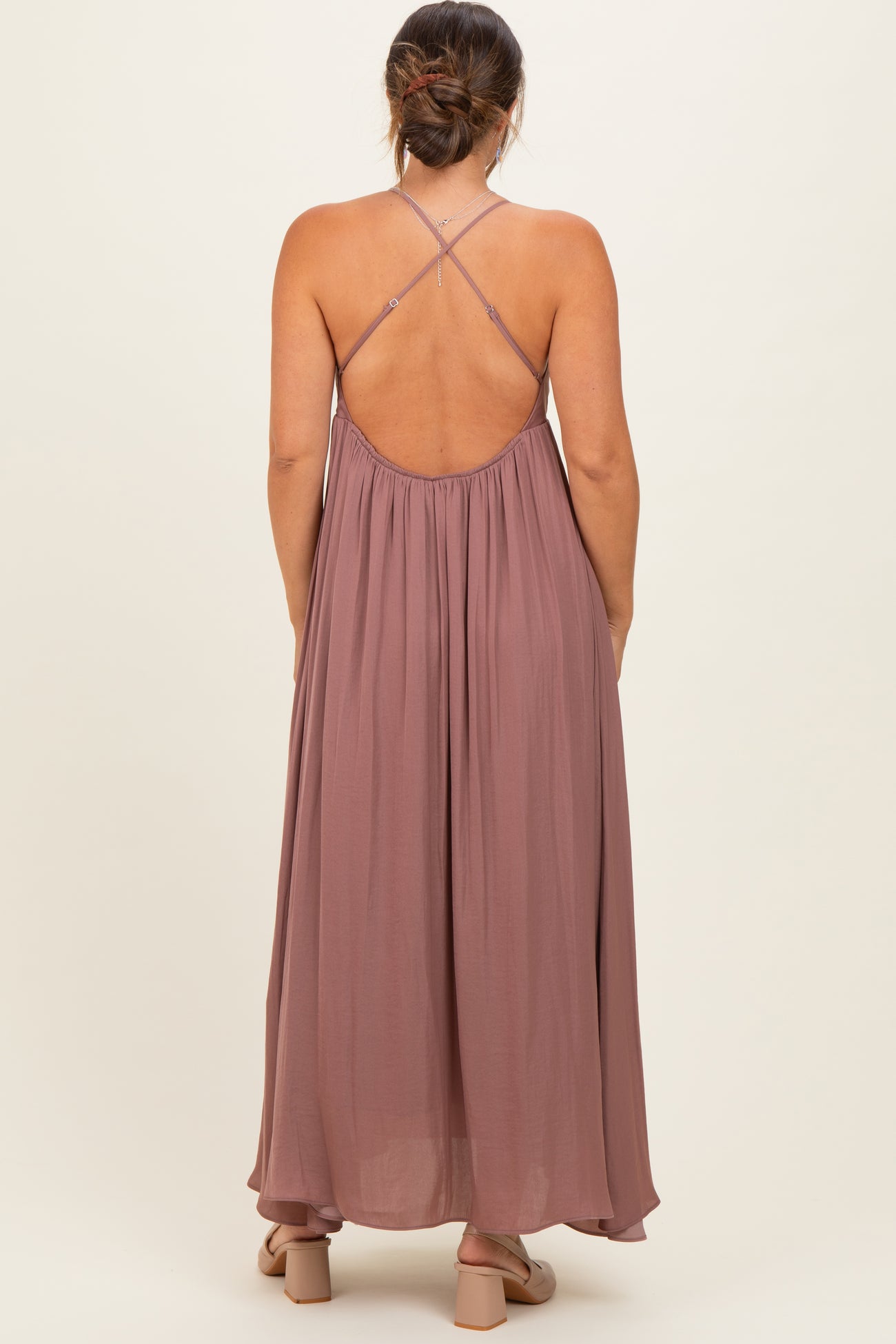 woman wearing a mauve maternity maxi dress with a strappy back design and flowing fabric