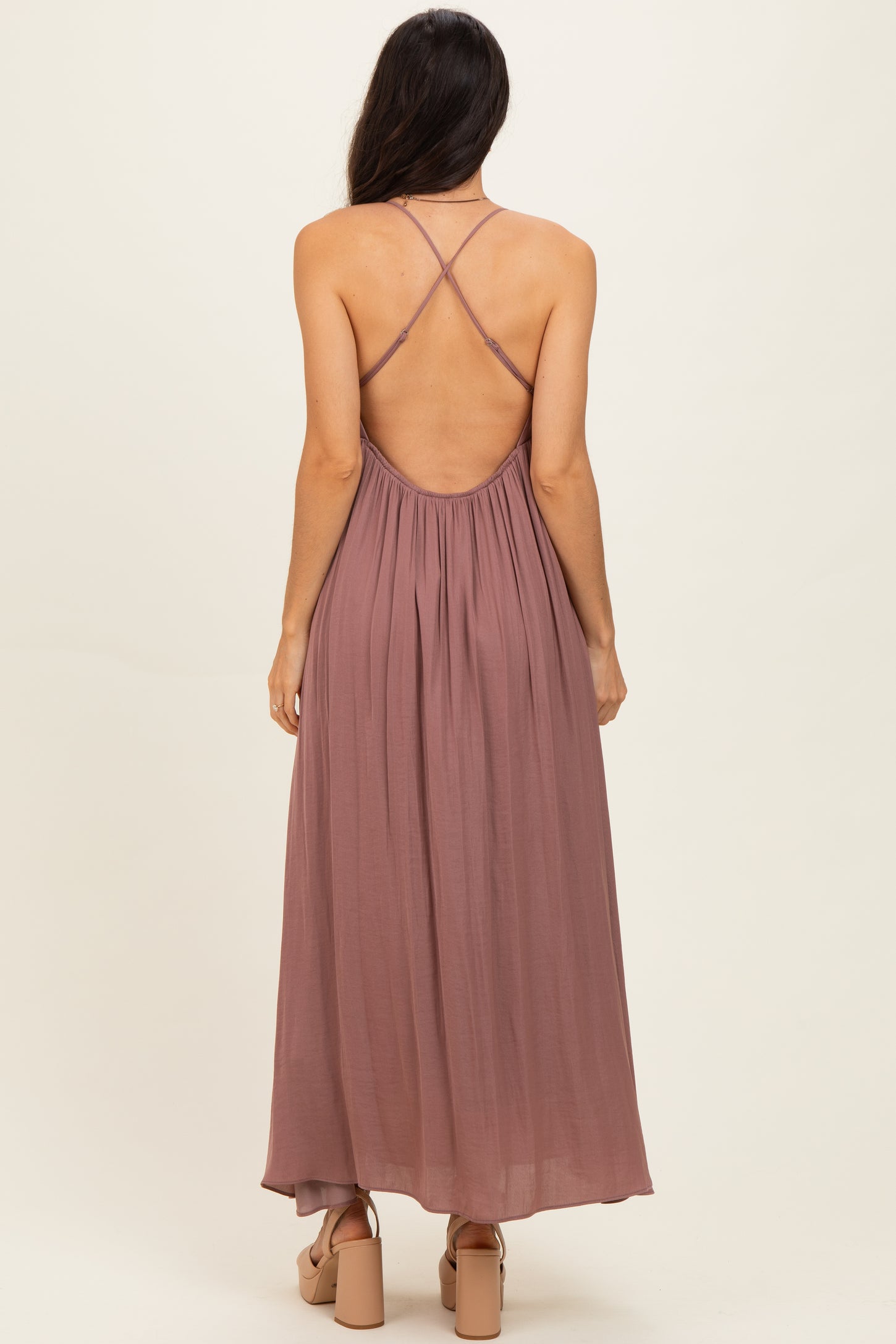 woman wearing a dusty mauve maxi dress with a crisscross back and flowy silhouette