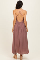 woman wearing a dusty mauve maxi dress with a crisscross back and flowy silhouette