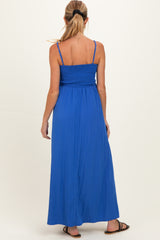 woman wearing a bright blue smocked back maternity maxi dress, showing a flowing skirt and adjustable straps