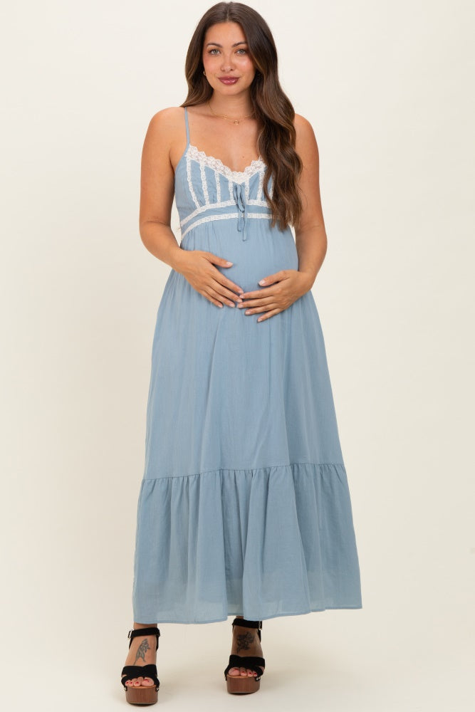 woman wearing a light blue maternity maxi dress with lace detailing and holding her baby bump