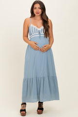 woman wearing a light blue maternity maxi dress with lace detailing and holding her baby bump