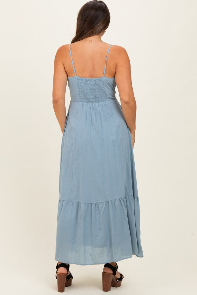 woman wearing a light blue maternity maxi dress with adjustable straps and a tiered skirt, showing her back