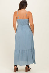 woman wearing a light blue maternity maxi dress with adjustable straps and a tiered skirt, showing her back