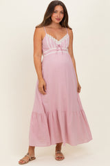 woman wearing a light pink maternity maxi dress with lace details and a baby bump visible