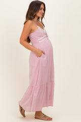 woman wearing a pink maternity maxi dress with lace details and pockets, showcasing her baby bump