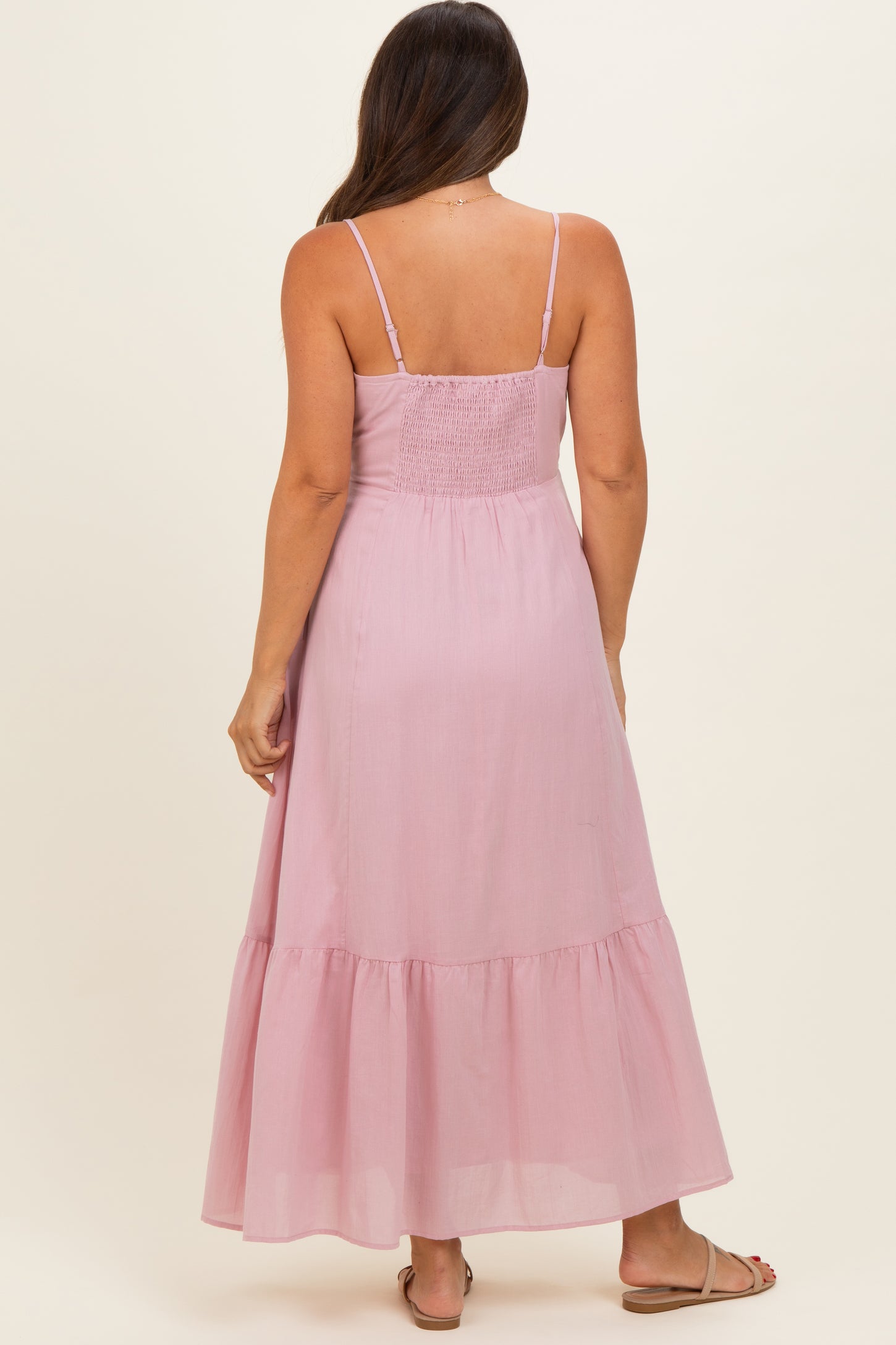 woman wearing a light pink maternity maxi dress with a smocked back and spaghetti straps