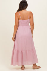 woman wearing a light pink maternity maxi dress with a smocked back and spaghetti straps