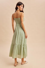 woman wearing a light green sleeveless maxi dress with a fitted bodice and tiered skirt, shown from the back