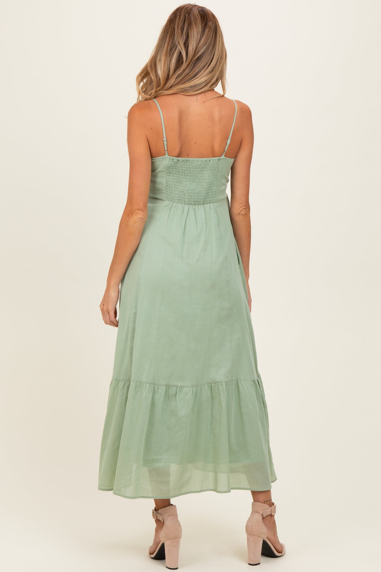 woman wearing a green maxi maternity dress with a smocked bodice and tiered skirt, seen from the back