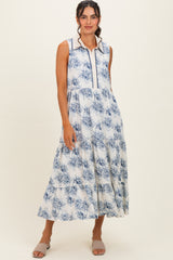 woman wearing a sleeveless white maxi dress with blue floral print and a collared neckline