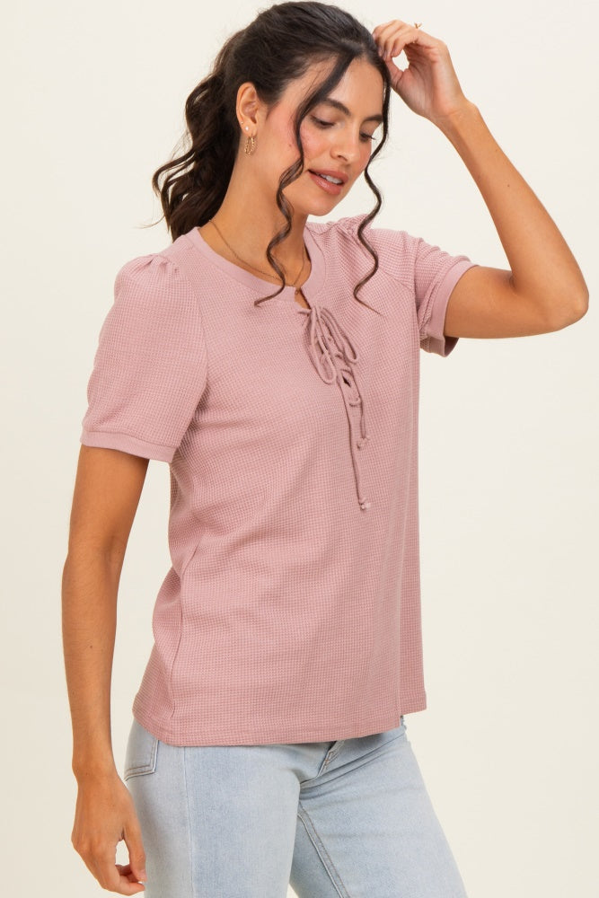woman wearing a pink short sleeve top with tie detail and puff sleeves, paired with light blue jeans