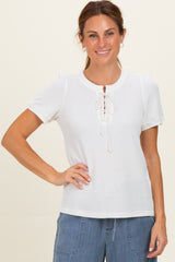 woman wearing a white short sleeve top with a lace-up front and puff sleeves