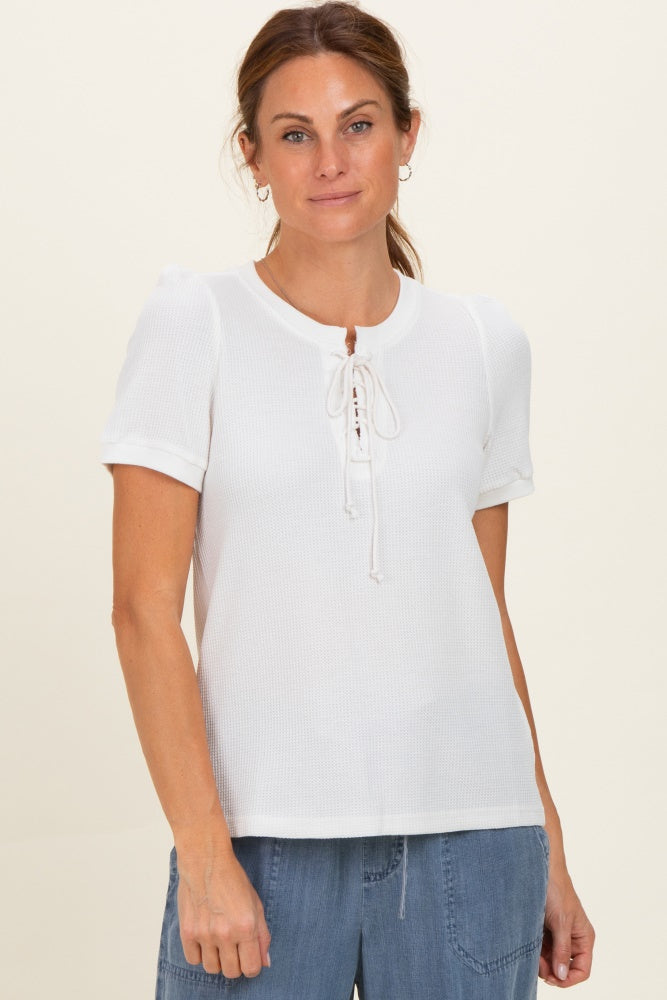 woman wearing a white short sleeve top with a lace-up detail and textured fabric