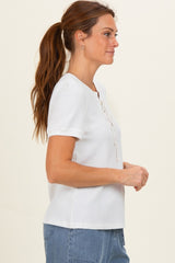 woman wearing a white short sleeve top with a lace-up front detail and a relaxed fit
