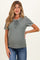 woman wearing a sage green short sleeve maternity top with lace-up front detail and a visible baby bump