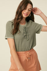 woman wearing a green short sleeve top with lace-up front and peach drawstring shorts