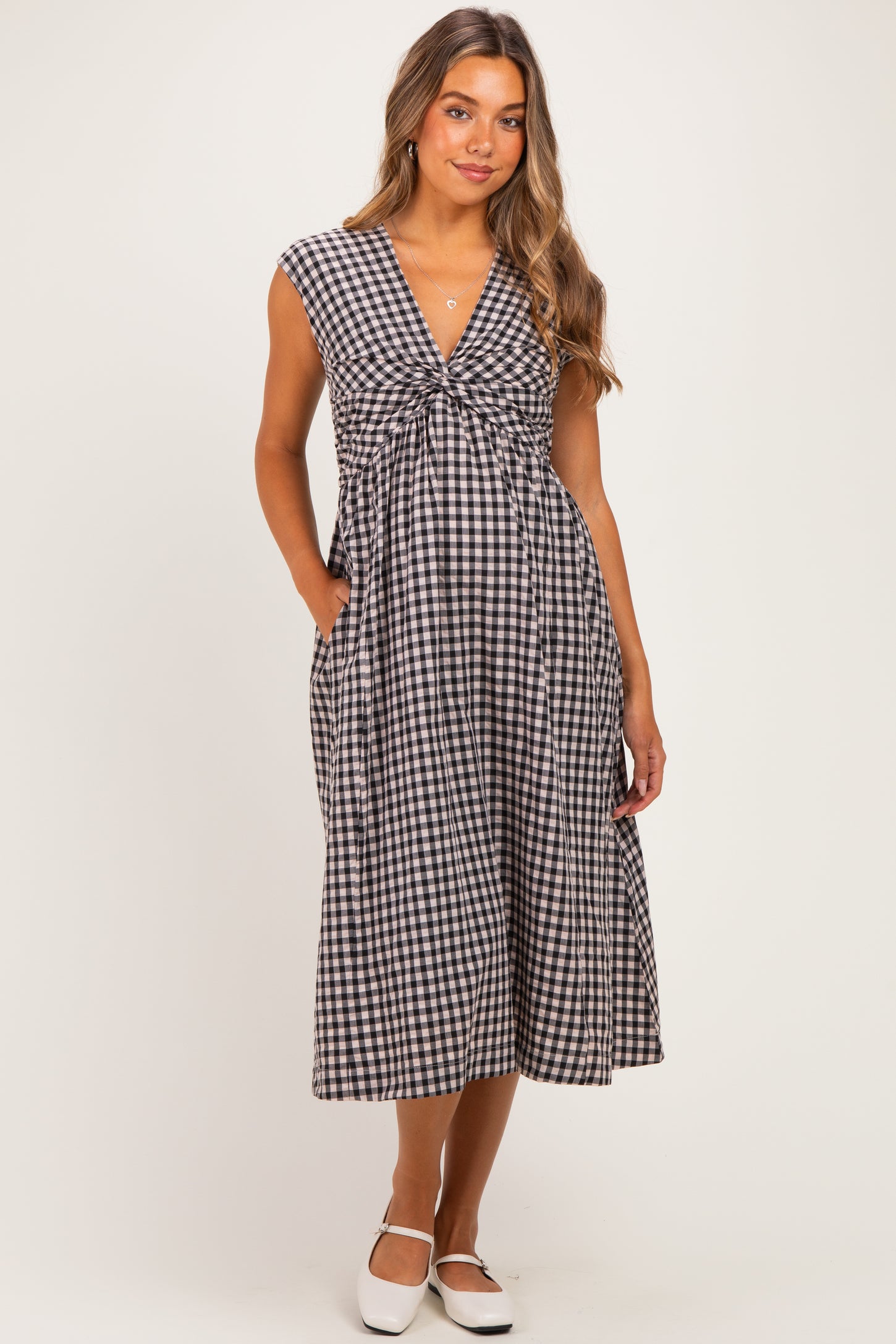 woman wearing a black and white gingham print maternity dress with a v-neck and pockets