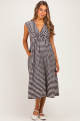 woman wearing a black and white gingham print maternity dress with a v-neck and pockets
