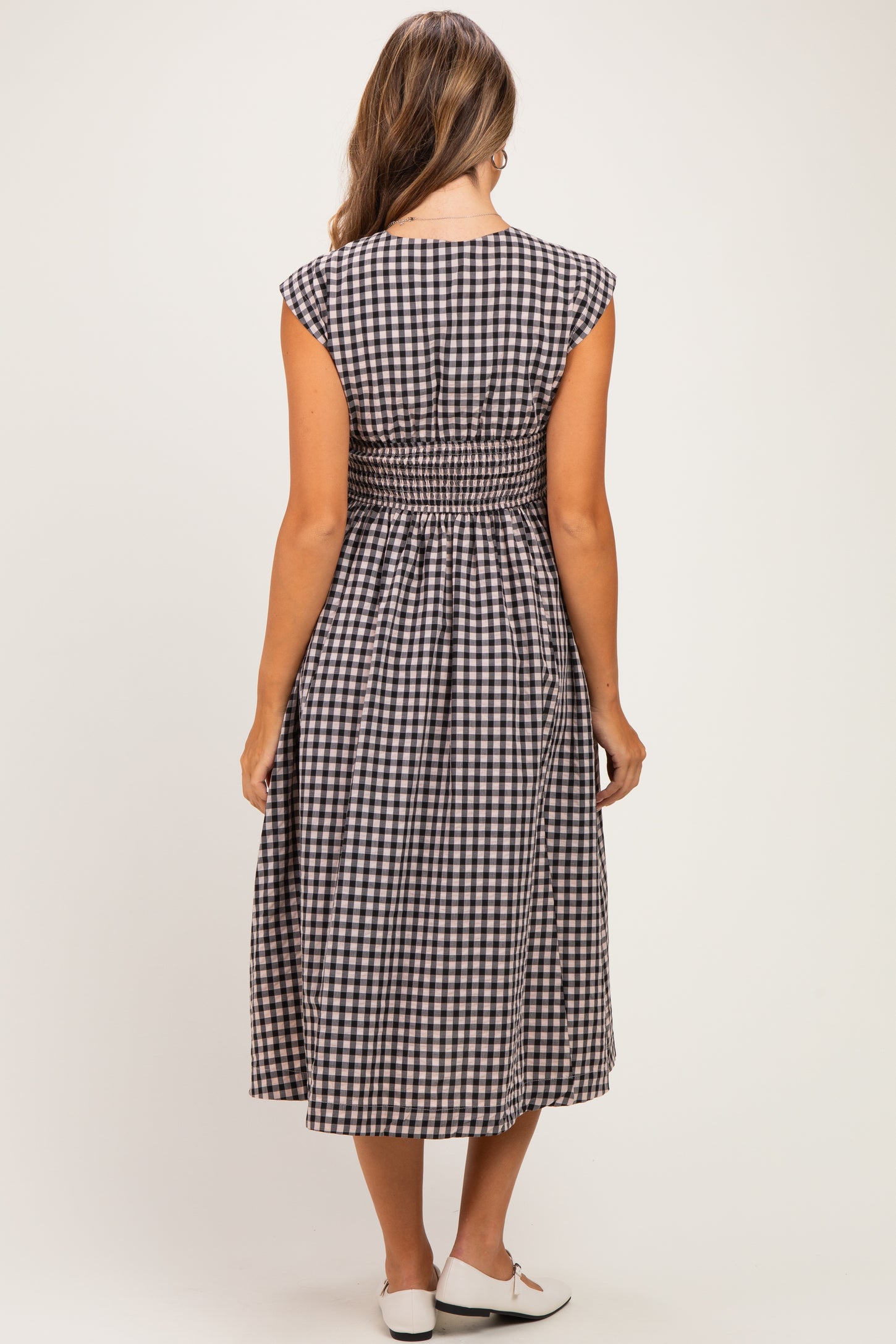 woman wearing a black and white gingham maternity dress with a smocked back detail