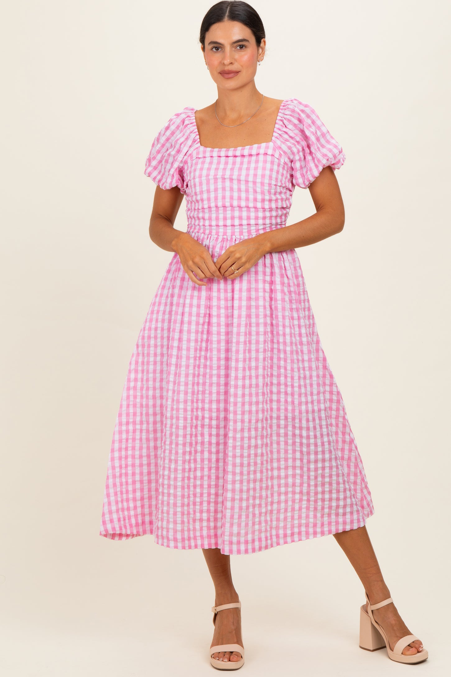 woman wearing a pink and white gingham midi dress with puff sleeves and a square neckline
