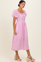 woman wearing a pink and white checked mid-length dress with puff sleeves and a square neckline
