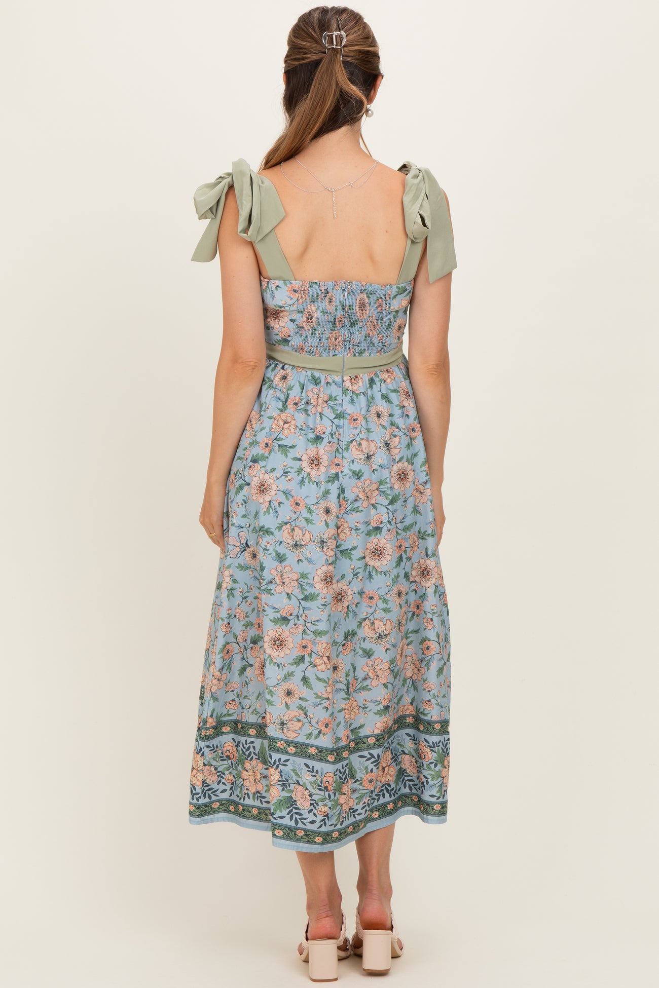 woman wearing a floral print maternity maxi dress with bow shoulder straps and a fitted bodice