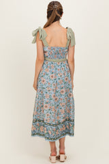 woman wearing a floral print maternity maxi dress with bow shoulder straps and a fitted bodice