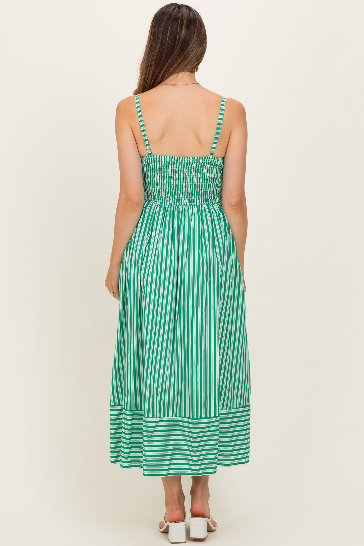 woman wearing a green and white striped maternity maxi dress with a smocked back and adjustable straps