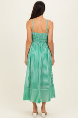 woman wearing a green and white striped backless maxi dress with smocking detail and a flowy skirt