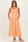 woman wearing an orange striped maxi dress with a smocked bodice and pockets, standing against a neutral background