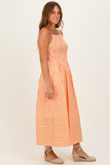 woman wearing an orange striped maxi dress with a smocked bodice and spaghetti straps, standing sideways