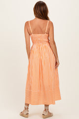woman wearing a back view of an orange and white striped midi dress with a smocked bodice and spaghetti straps
