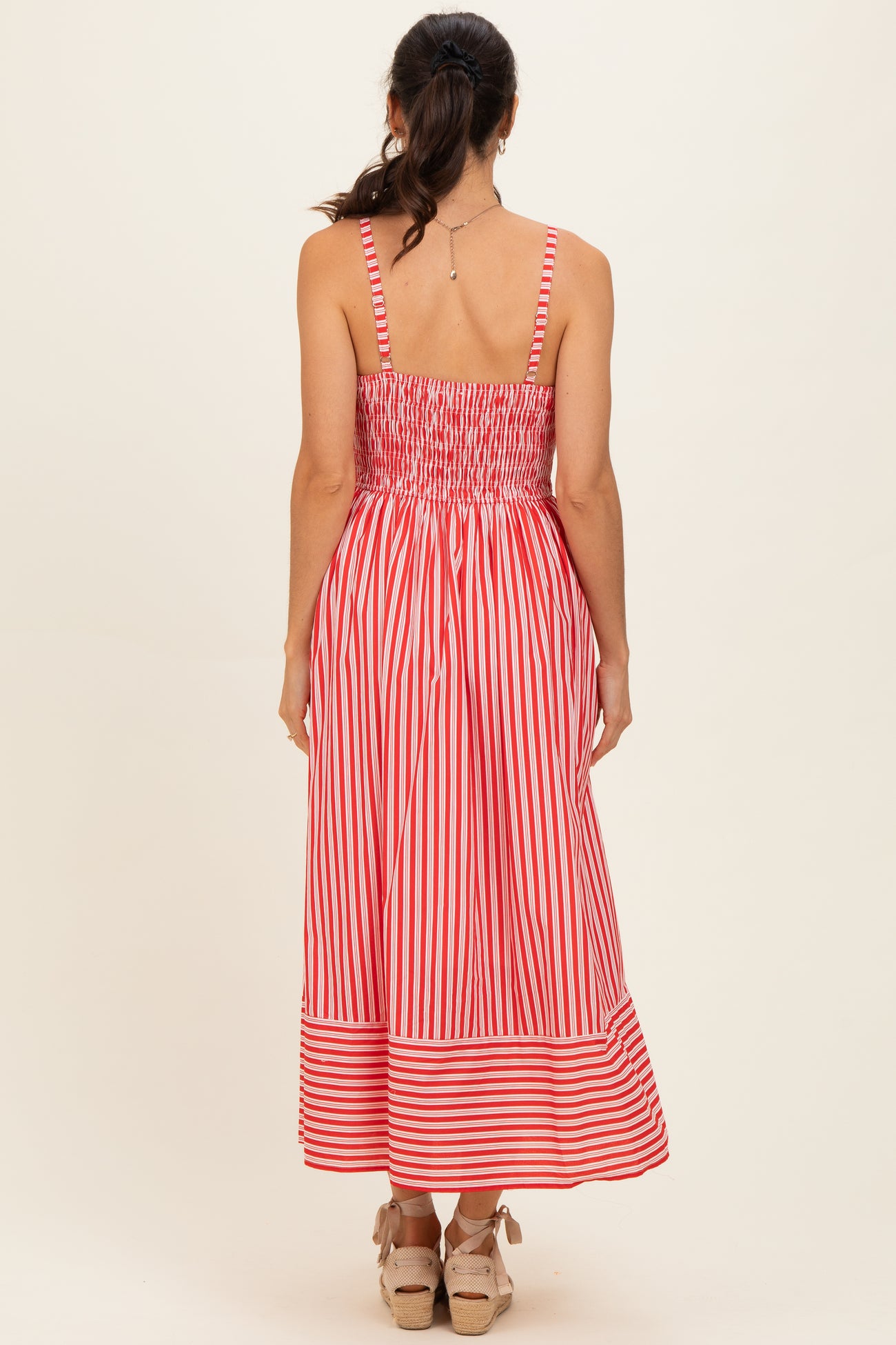 woman wearing a red and white striped midi dress with a smocked bodice and an open back view