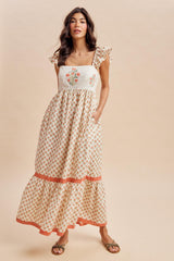 woman wearing a white floral embroidered maxi dress with ruffled sleeves and a tiered hemline