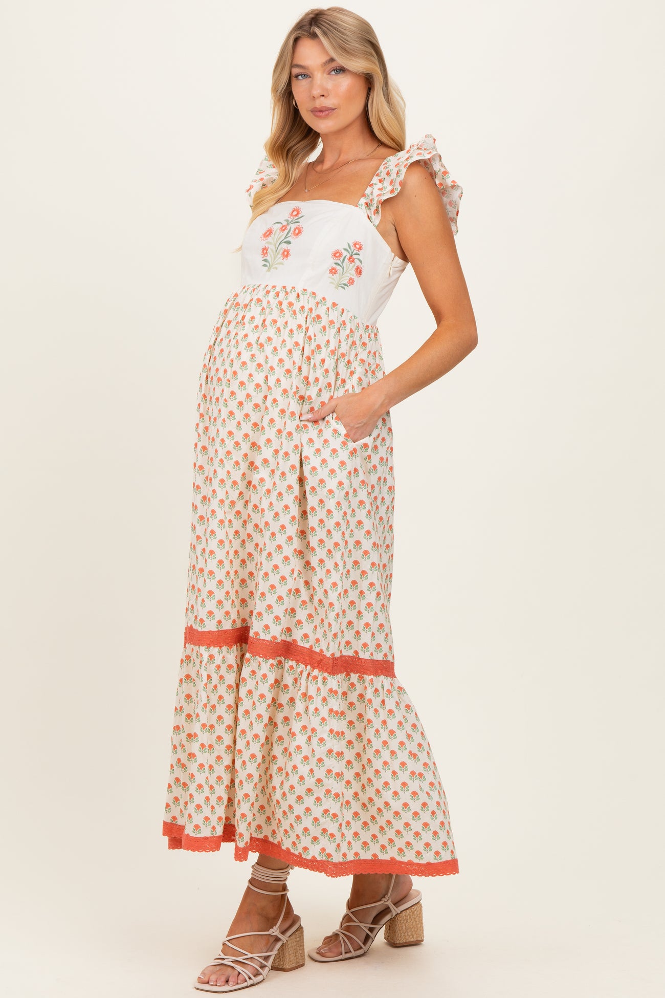 woman wearing a floral print maternity maxi dress with ruffle straps and a visible baby bump