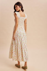 woman wearing a floral print maxi dress with puff sleeves and tiered hem, viewed from the back