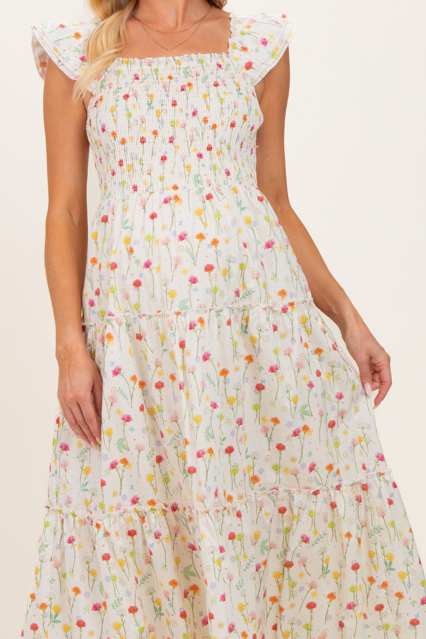 woman wearing a floral print maternity maxi dress with smocked bodice and ruffled sleeves, showcasing her baby bump