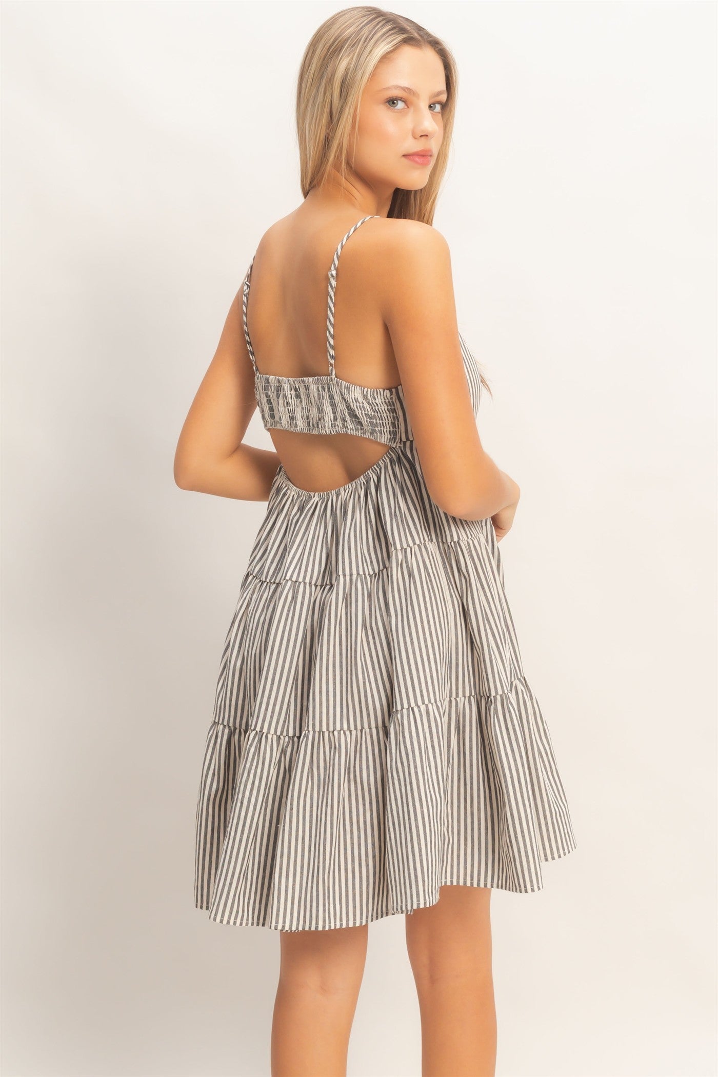 woman wearing a black and white striped tiered sundress with adjustable straps and an open back