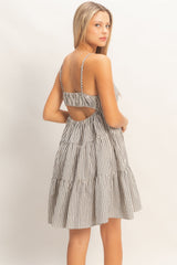 woman wearing a black and white striped tiered sundress with adjustable straps and an open back