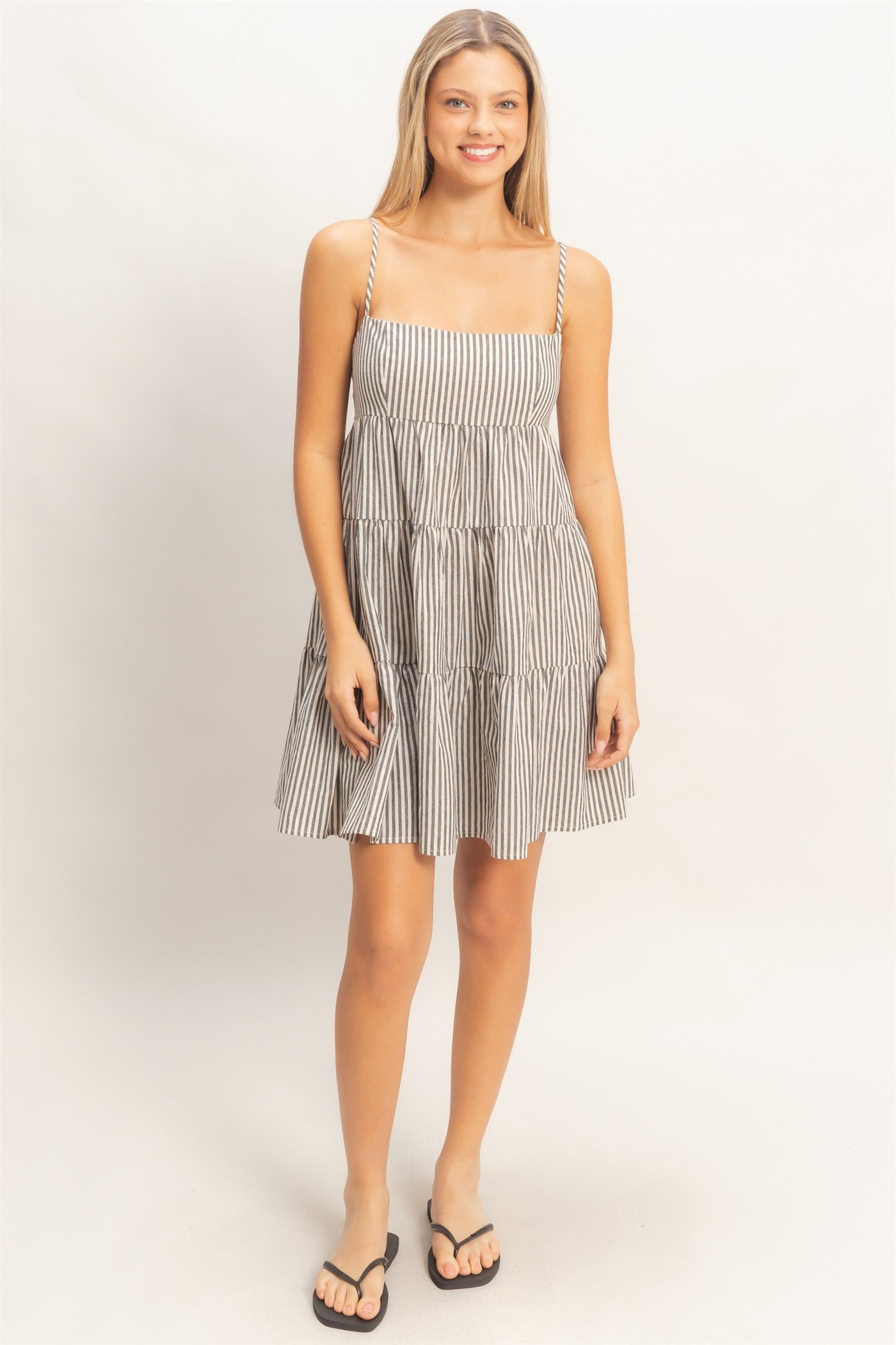 woman wearing a black and white striped smocked sundress with adjustable spaghetti straps and a tiered skirt