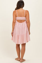 woman wearing a pink and white striped maternity dress with a tiered skirt and open back design